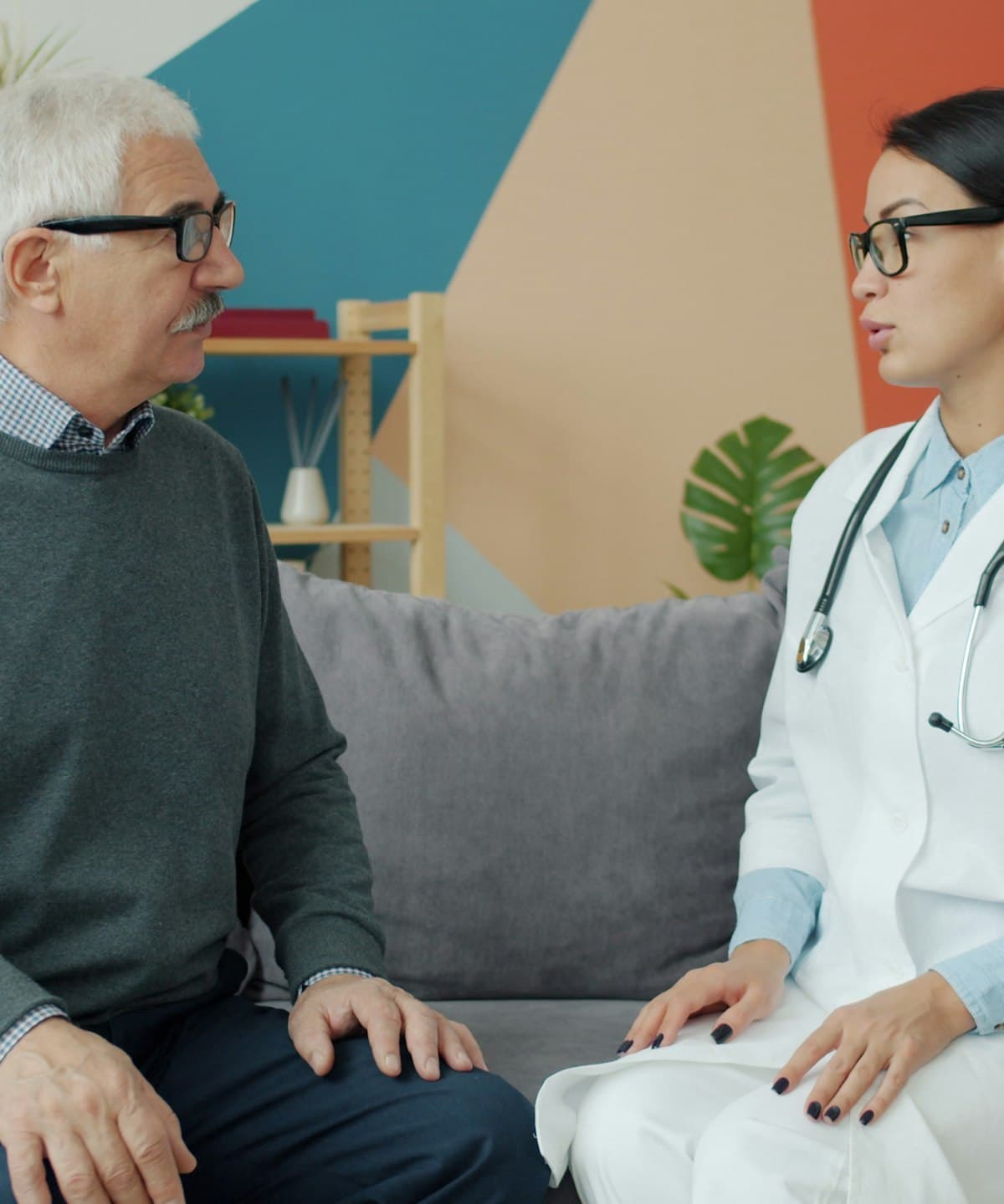 A nurse on a home visit, with a reassuring hand on the shoulder of an older man.